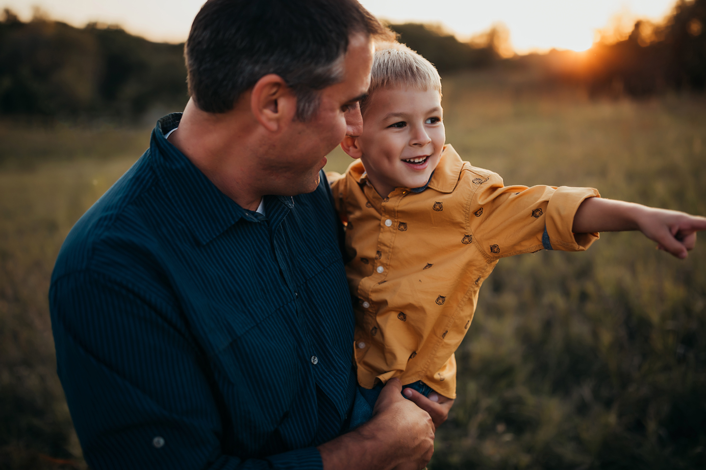 Kevin holding his son in a field with sun setting in the background